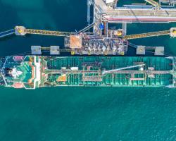 Top-down view of cargo ship being refueled and loaded